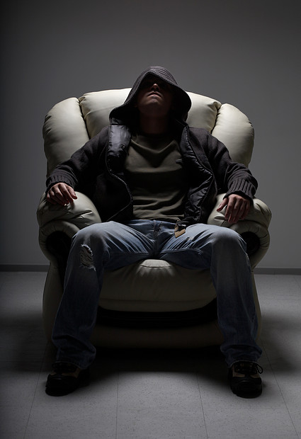 坐白色椅子上的危险人物的黑暗肖像