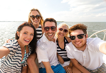 度假,旅行,海洋,友谊人的微笑的朋友坐游艇甲板上自拍图片