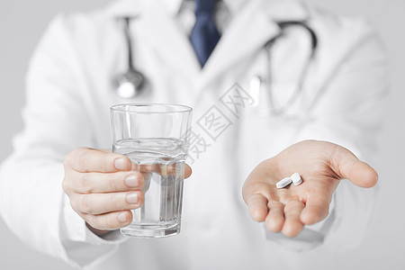 医生的手给白色药丸杯水的照片图片