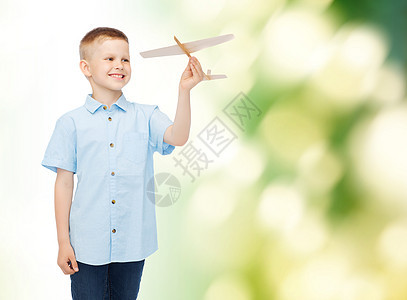 梦想,未来,爱好,生态童的微笑的小男孩手里着木制的飞机模型绿色的背景上图片