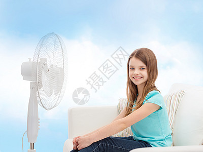 夏天,天气设备微笑的小女孩坐沙发上,家里大风扇图片