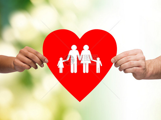健康,爱,收养关系的特写多种族夫妇的手大红心与家庭孩子的绿色背景图片