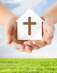 宗教,基督教慈善近距离的妇女手纸屋与基督教十字符号蓝天上与草的背景图片