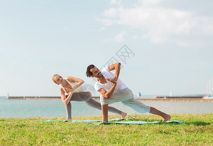 健身,运动,友谊生活方式的微笑的夫妇户外垫上瑜伽练图片