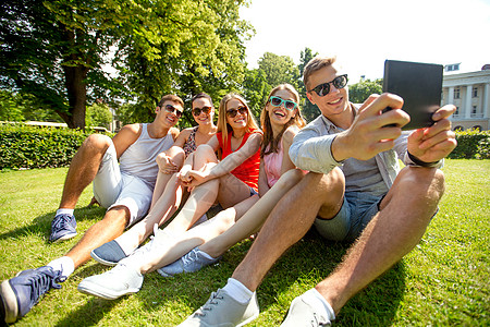 校园wifi友谊,休闲,夏天,技术人的群微笑的朋友与平板电脑电脑坐公园里自拍背景