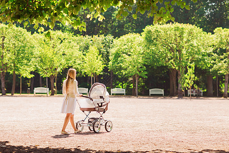 家庭,孩子父母的快乐的母亲与婴儿车公园后走图片