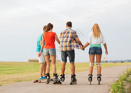 假期,爱友谊的群青少带着溜冰鞋滑板后骑户外图片