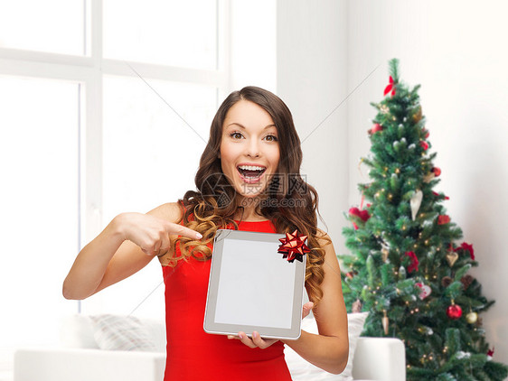 诞节,技术,礼物人的微笑的女人穿着红色连衣裙,客厅诞树背景上空白的平板电脑电脑屏幕图片