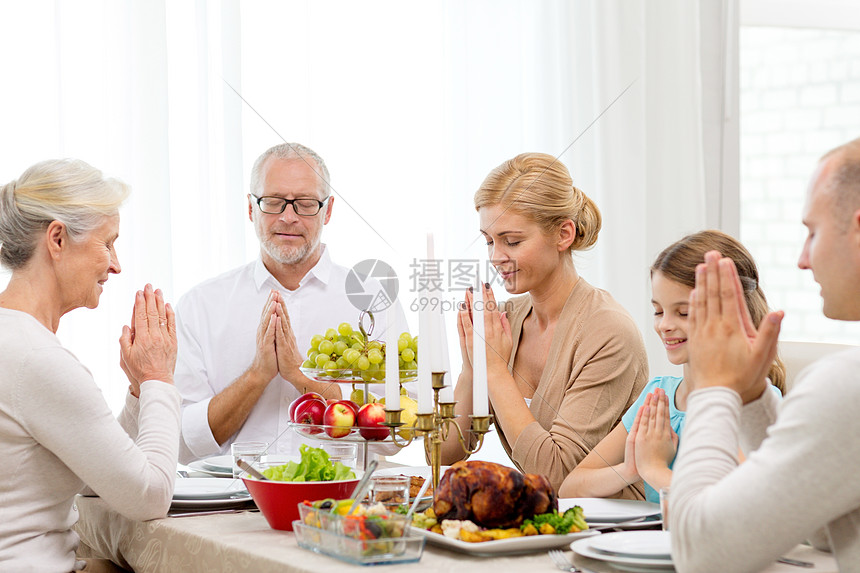 家庭,假期,世代人的微笑的家庭家里吃饭祈祷图片