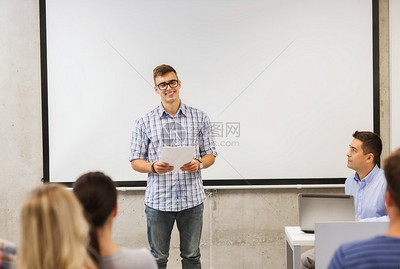 教育,高中,技术人的微笑的学生男孩戴着眼镜,笔记本电脑站学生前,老师教室里图片