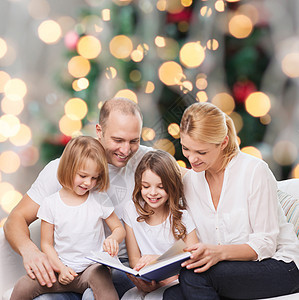 家庭,童,假期人微笑的母亲,父亲小女孩客厅诞树背景上看书图片