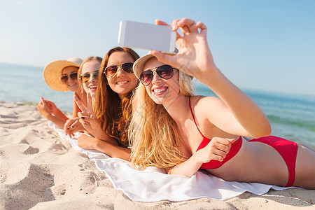 暑假,旅游,技术人的群微笑的女人戴着太阳镜,海滩上用智能手机自拍图片