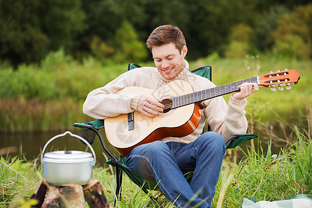 冒险,旅行,旅游人的微笑的人与吉他烹饪食物篝火露营图片素材