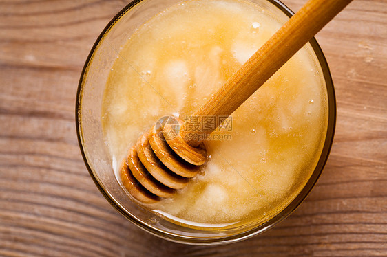 蜂蜜滴木桌上的璃碗里图片