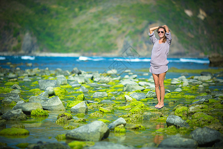 女人独自走绿色的礁石上图片