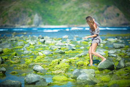 女人独自走绿色的礁石上图片