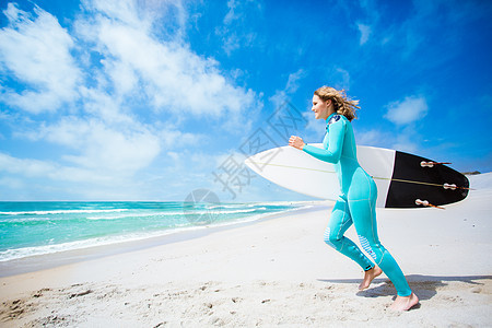 冲浪女孩带着冲浪板海滩上跑步图片