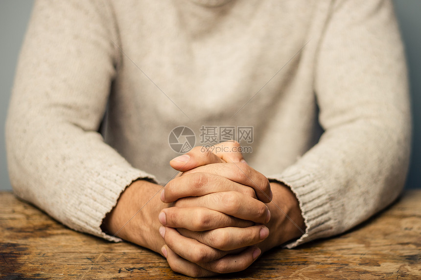 男人桌子上,双手交叉祈祷图片