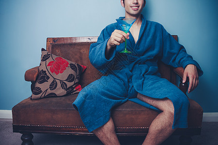 穿着浴袍的男人坐沙发上喝鸡尾酒图片
