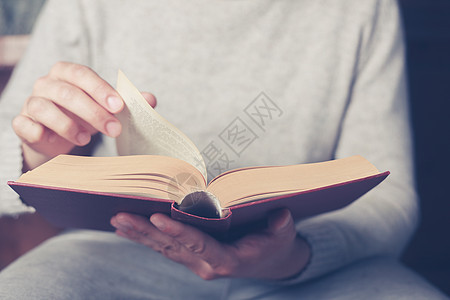轻人坐沙发上翻着本书的书页图片