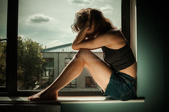 伤心难过的女人坐窗台上图片