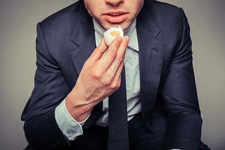 个坐办公椅上的商人正吃鸡蛋图片