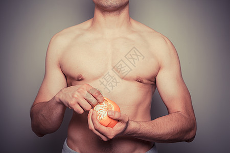 个运动的轻无衫男子正剥橘子图片