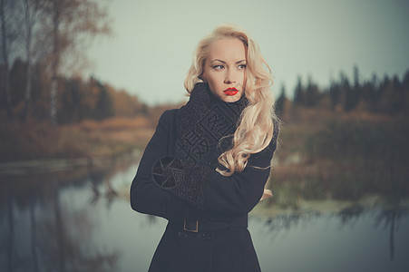 河岸上穿着黑色外套的美丽优雅的女人图片