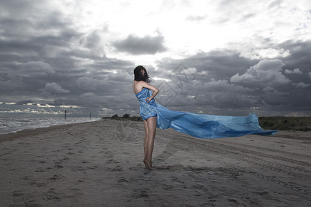 高加索模特穿着长裙海滩上摆姿势暴风雨的日落图片