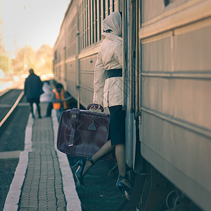 时尚的女人进入火车车厢着手提箱图片