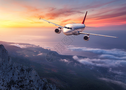 飞机日落时飞过低云风景与客机,山脉,海洋橙色的天空与红色的云夏天客机商业旅行欧洲商业飞机图片
