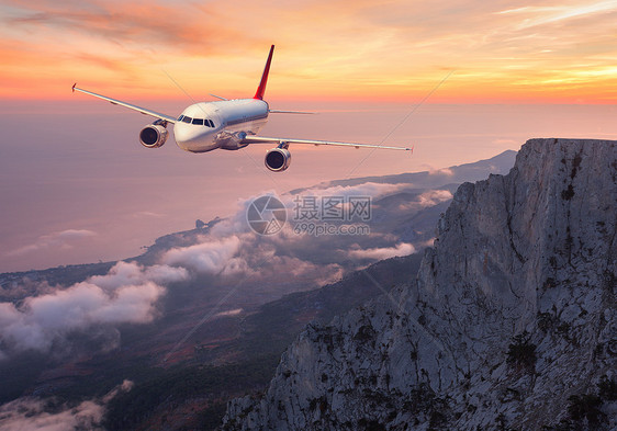 飞机日落时飞过岩石云层夏季客机山脉海洋橙色多云天空的景观客机欧洲的商务旅行商业飞机图片