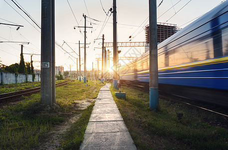 日落时铁路轨道上运动的高速客运列车火车站模糊的现代通勤列车,铁路红绿灯映衬着五彩缤纷的蓝天云彩工业景观图片
