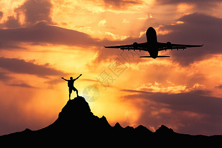 个站立的快乐男人的飞机轮廓日落时,飞机站立的快乐的人的轮廓举的手臂山峰上夏季景观与着陆客机飞行橙色天空与云图片