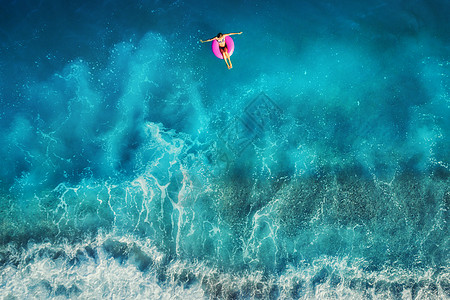 鸟瞰轻女子游泳粉红色的游泳环透明的绿松石海,土耳其奥卢德尼斯夏天的海景与女孩,美丽的波浪,蔚蓝的水日落无人机的顶图片