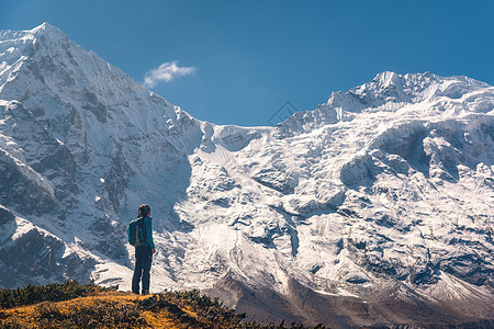 站山上的轻女人,看着神奇的喜马拉雅山脉风景与旅行者,高岩石与雪峰,蓝色的天空秋天尼泊尔生活方式,旅行喜马拉图片