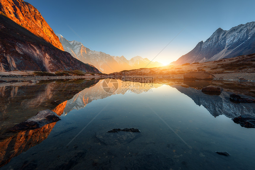 美妙的景观,高岩石与照亮的山峰,石头山湖,反射,蓝天阳光日出尼泊尔喜马拉雅山脉的惊人景象喜马拉雅山图片
