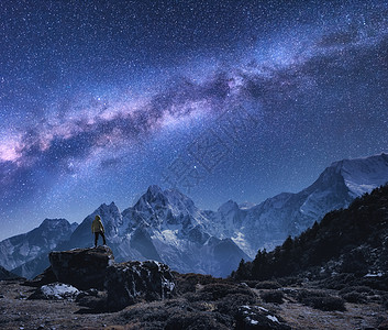 银河山脉的尼泊尔的夜晚,站石头上的人,山脉星空岩石上雪峰,天空上星星徒步旅行夜风景与明亮的银图片