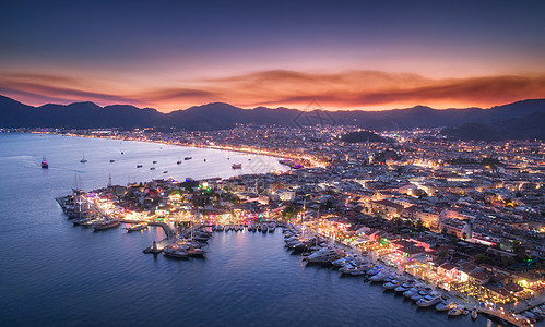 鸟瞰船只美丽的城市马尔马里斯,土耳其风景与船码头湾,海洋,城市灯,山脉,红色的天空,黄昏的云无人机的顶部视图图片