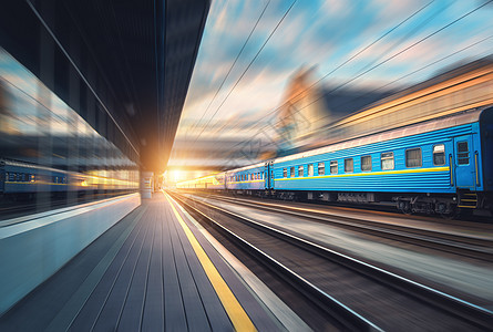 日落时,火车站里辆蓝色货车的漂亮火车工业景观与现代列车,铁路,铁路平台,建筑,多云天空与运动模糊效应图片
