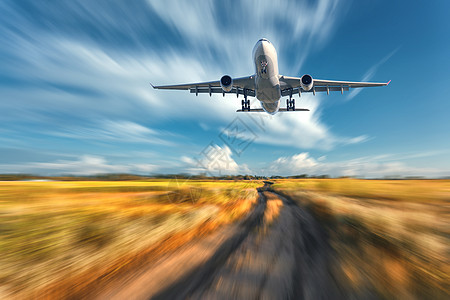 运动模糊效应的飞机风景与飞行的客机模糊的蓝天与云,橙色的草地与小径日落客机正降落商用飞机图片