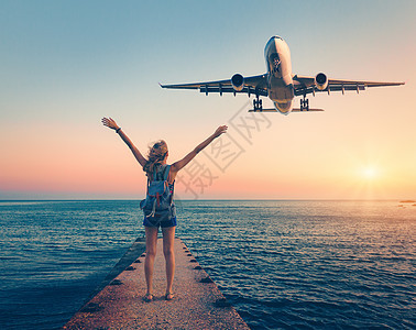 日落时的飞机女人夏天的风景,女孩站海上码头,举手臂飞行的客机女人降落商业飞机黄昏生活方式旅行图片