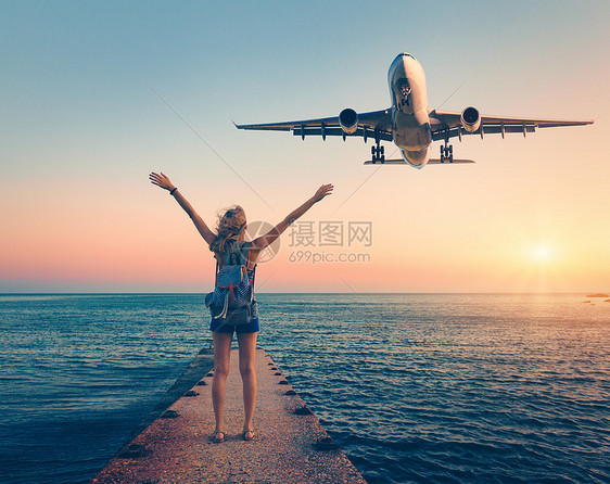 日落时的飞机女人夏天的风景,女孩站海上码头,举手臂飞行的客机女人降落商业飞机黄昏生活方式旅行图片