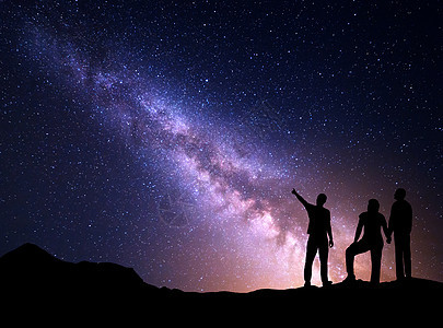 银河里个站着的轻人的剪影,指着夜空他的父母五颜六色的夜景美丽的宇宙,旅行背景与天空充满星星图片