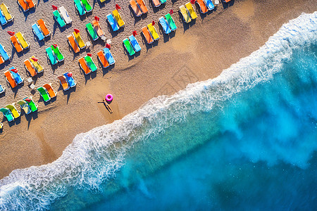 鸟瞰躺海里的女人,带着游泳环,土耳其的Oludeniz夏天的场景与轻的女孩,蓝色的水,波浪沙滩与五颜六色的躺椅日落图片