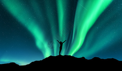 挪威山上站立的女人的极光剪影,举手臂北极光快乐的女孩星空,绿色的极地灯夜风景北极光旅行图片