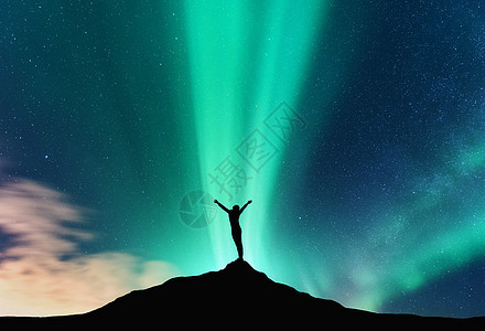 北极光个快乐女人的轮廓挪威山上站立的女人的极光剪影,举手臂北极光快乐的女孩星空,绿色的极地灯夜风景图片