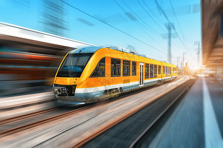 明亮的天,高速橙色列车火车站上运动现代城际列车铁路站台上运动模糊效应工业铁路上的客运通勤列车旅行高图片