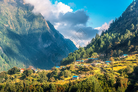 山上的个小村庄,日落时,阳光照耀着群山蓝天,云层密布夏季景观与房屋,田野与草,花园,绿树尼泊尔乡村景色旅行图片