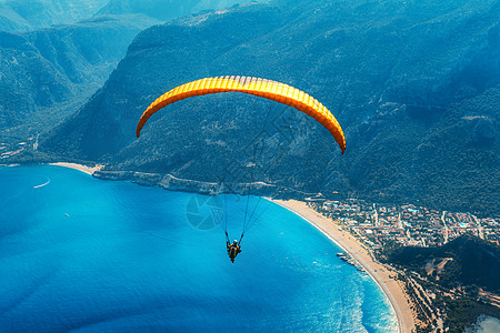 人与水滑翔天空中滑翔伞串联飞行海上与蓝色的水,海滩山脉日出鸟瞰滑翔伞蓝色泻湖奥卢德尼兹,土耳其极限运动景观背景